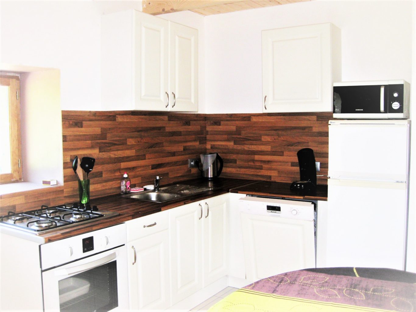 Cuisine équipée tout confort Cuisine moderne avec meubles blancs, plan de travail en bois et appareils électroménagers.