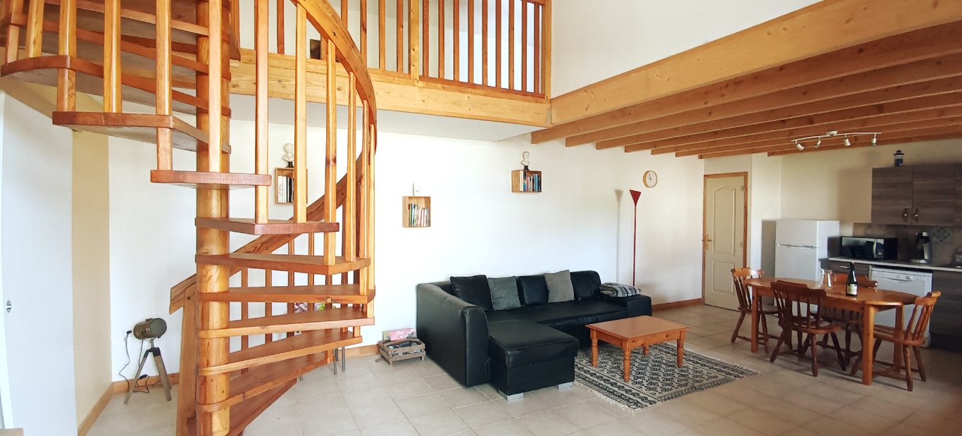 Séjour spacieux avec canapé convertible Intérieur d'un salon lumineux avec un escalier en colimaçon, un canapé et une table à manger.